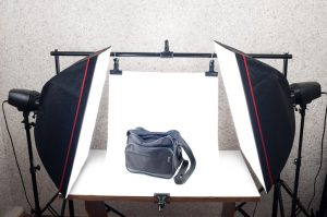 A bag is positioned between two light boxes and a white background for professional photography.