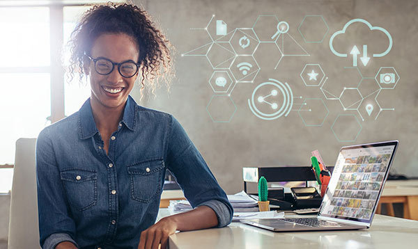 A woman with a laptop with several symbols hovering nearby.