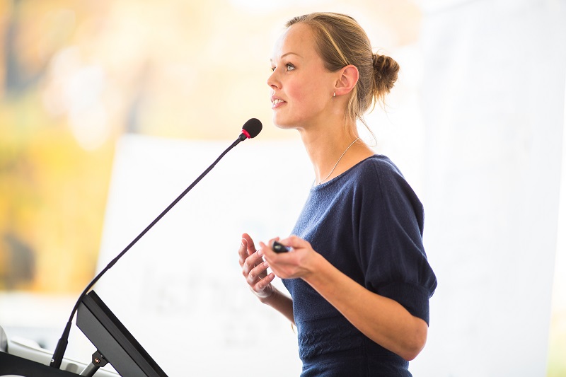 A woman is giving a speech in front of a microphone.