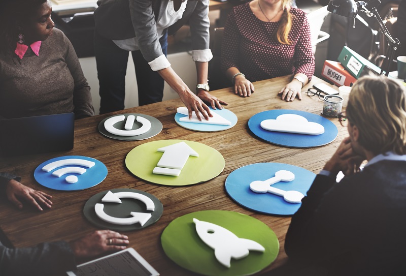 A team of five persons reviewing symbols spread on a table.