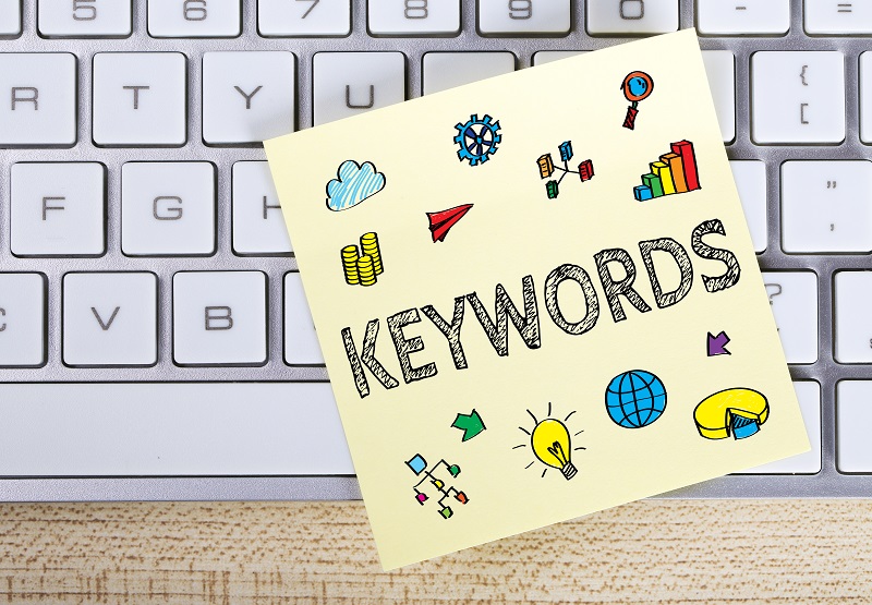 A picture of a keyboard with a sticky note on it that says 'keywords'.