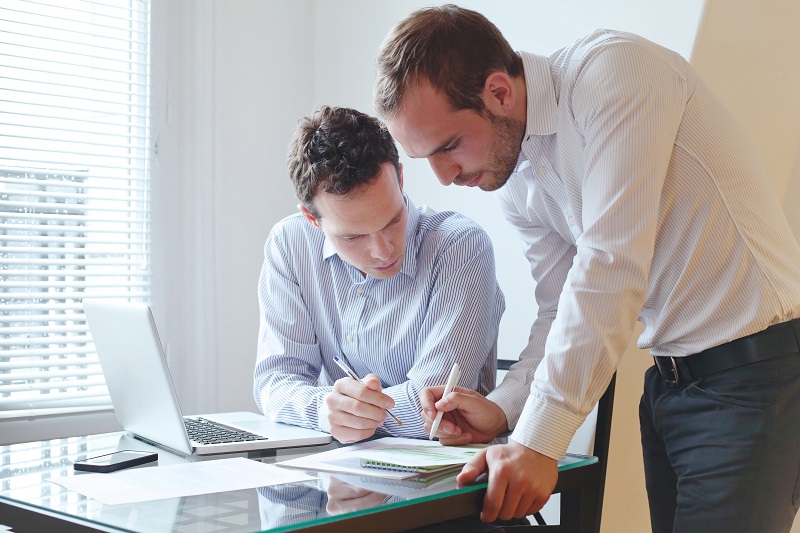 Two male coworkers are having a discussion in their office.