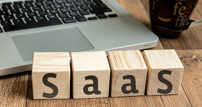 A picture of a laptop with building blocks in front of it that spell 'SaaS'.