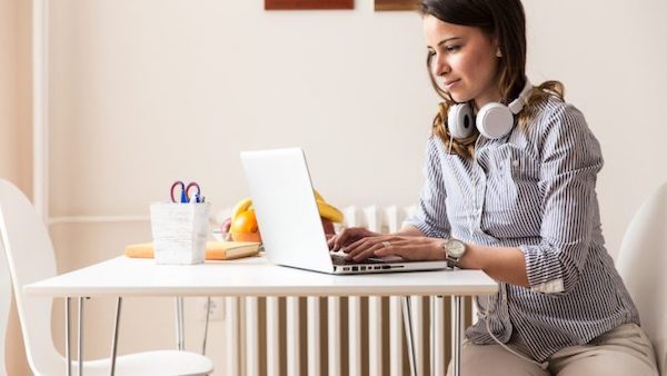 woman sat at table working on a laptop