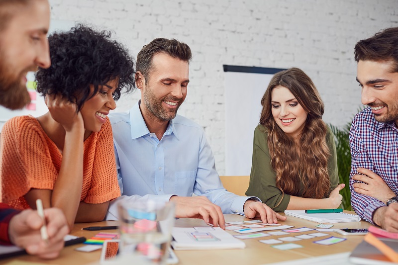 An office team glances over some notecards on the table.