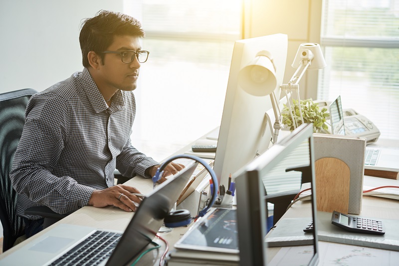 A man uses multiple computers to work.