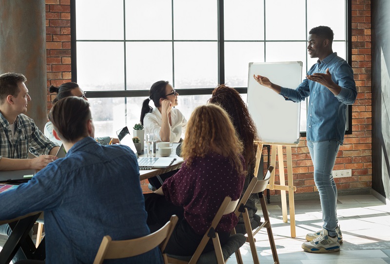 A young man leading a meeting at work.