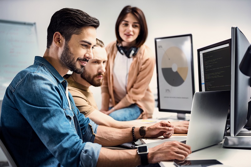 Two male and one female worker using different computers for graphics.