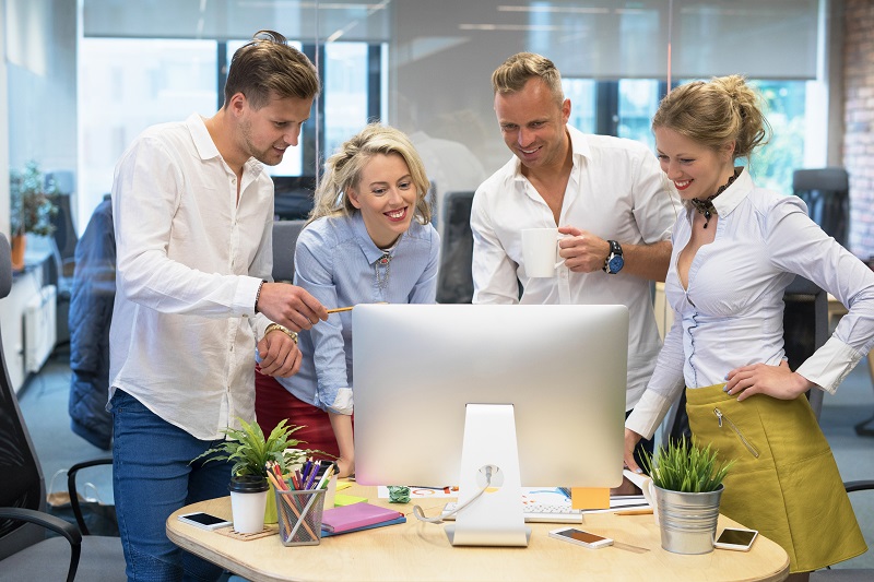 A group of young workers looking at a screen at an office.