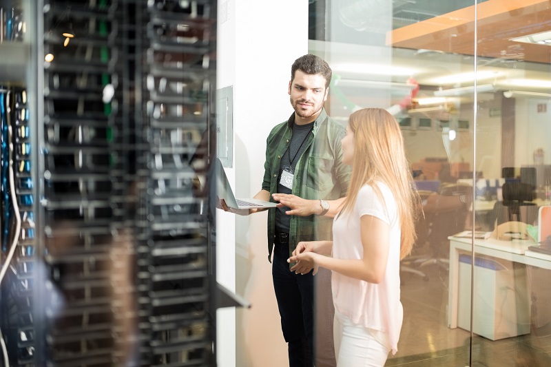 A man and woman coworkers review a data server.