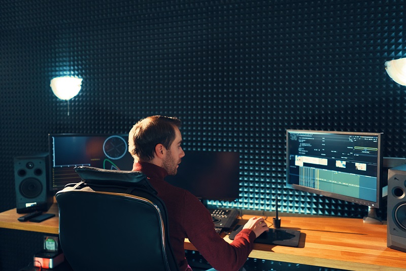 A young man video editing on a computer.