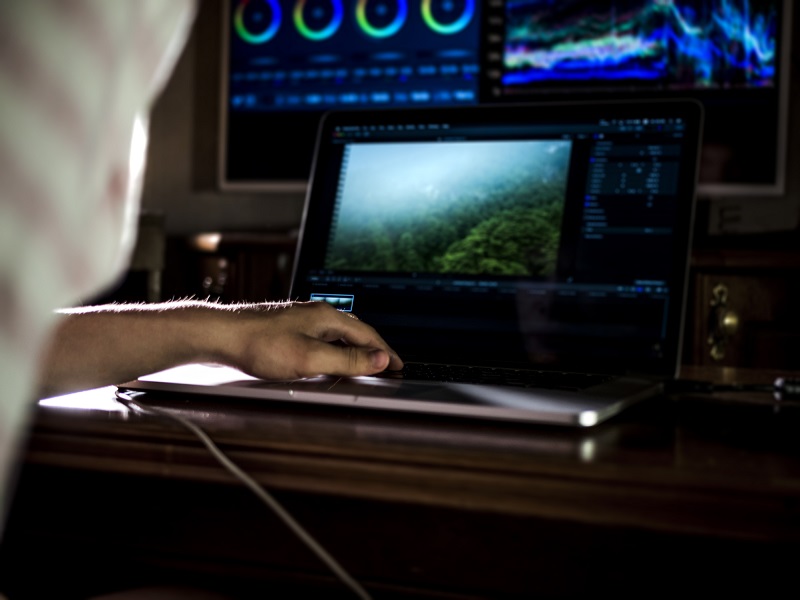 A man video editing using a laptop.