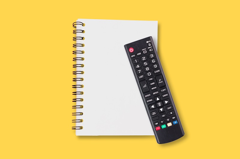 A picture of a remote control on top of a notebook.