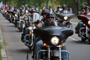 Eine Gruppe von Motorradfahrern, die im Korso auf der Straße unterwegs sind.
