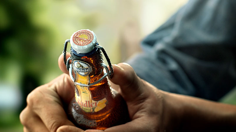 Eine Person hält eine Bierflasche.