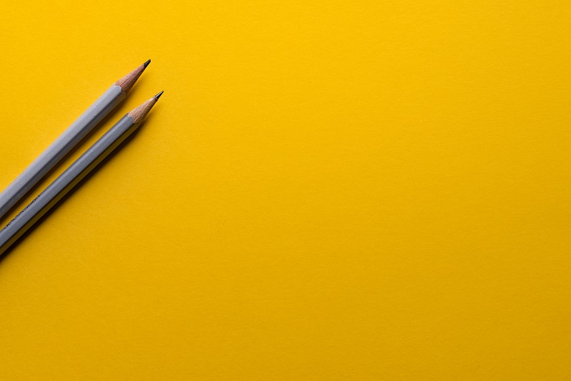 Two grey pencils on a yellow sheet.