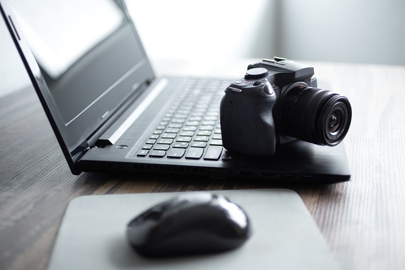 A camera sitting atop a laptop.