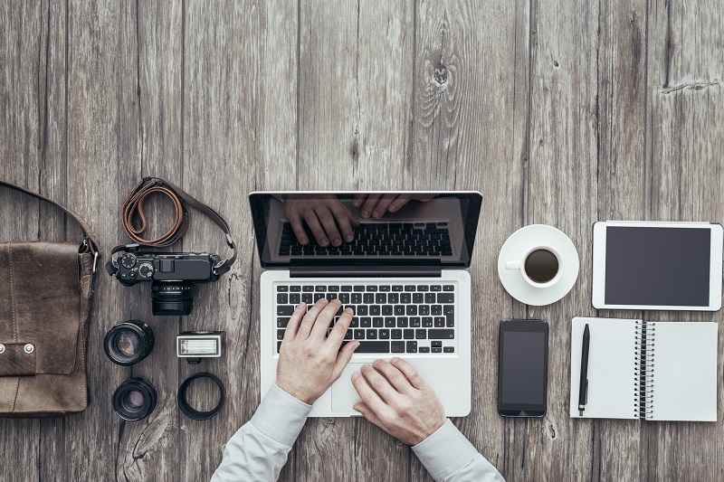 A person uses a laptop alongside a camera.