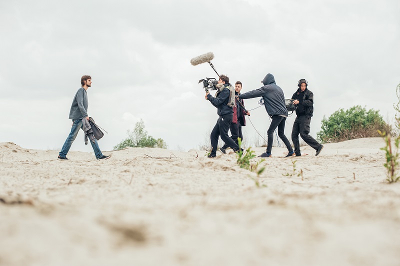 A picture of an actor being filmed walking in the desert.