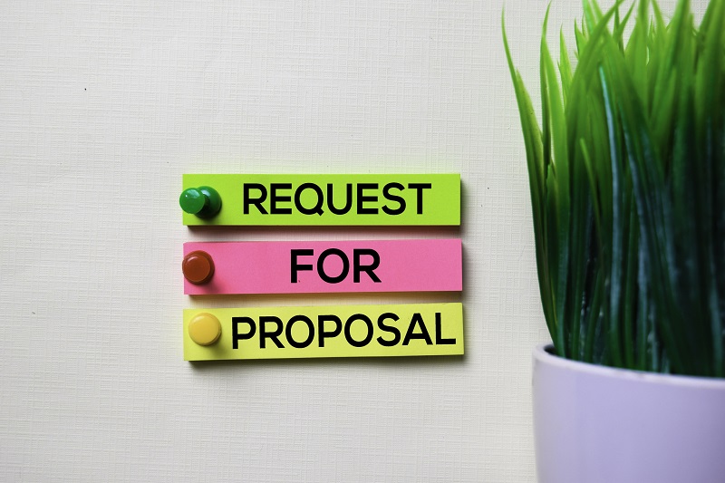 A plant next to a sign that reads 'Request For Proposal'.