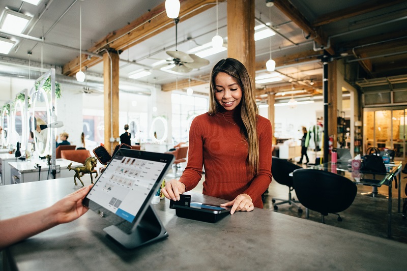 A woman swipes her credit card at a store.