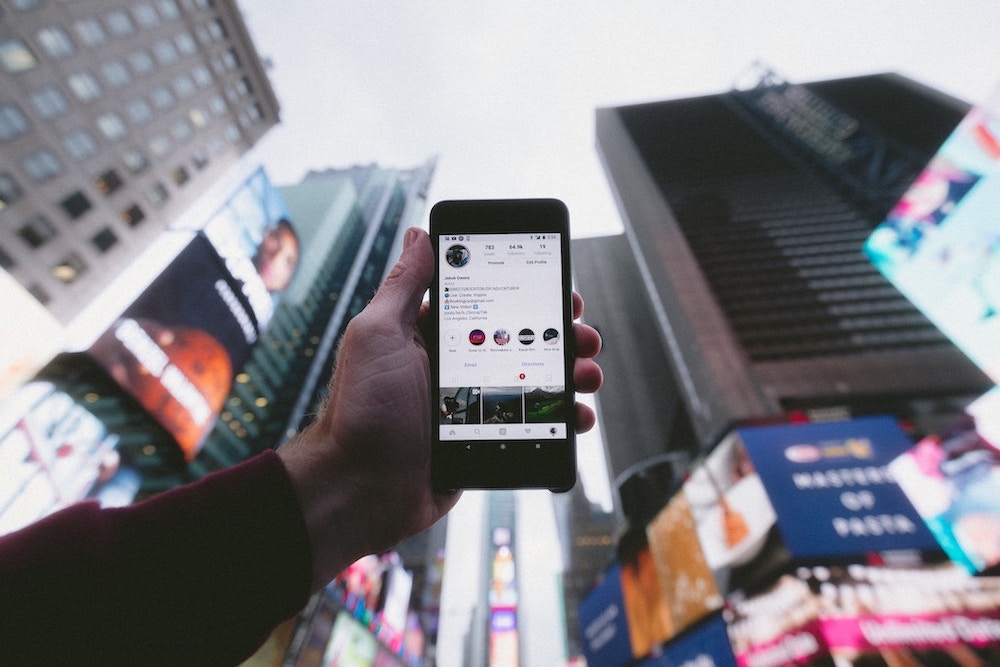 A person holding up a mobile phone in a city.