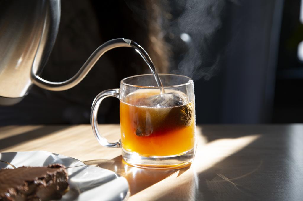 A photograph of hot water being poured onto a tea bag.