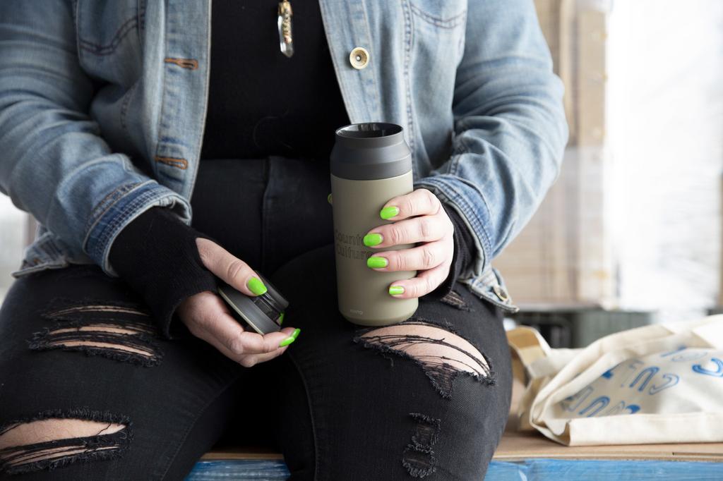 A photo of a person holding a thermos.