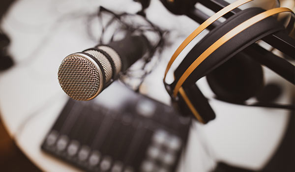 A microphone on a desk next to headphones.