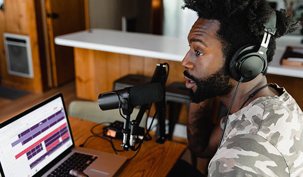 A young man recording a podcast on his laptop.