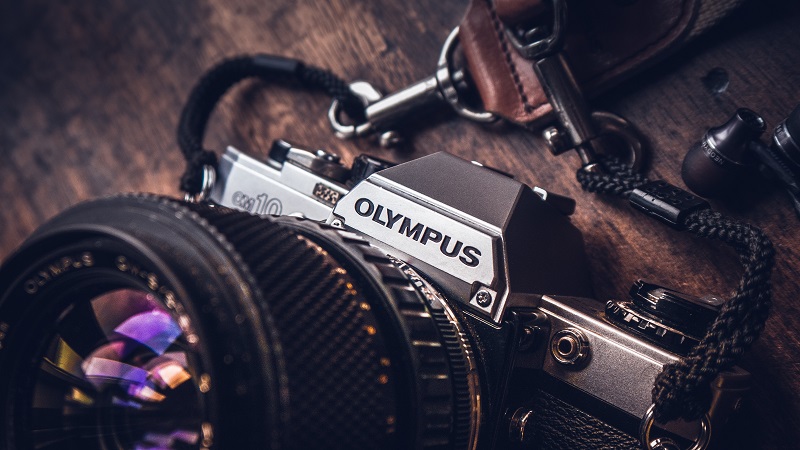 An olympus camera on a wooden desk.