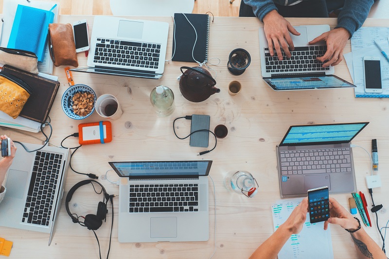 A group of laptops on a desk being used by workers.