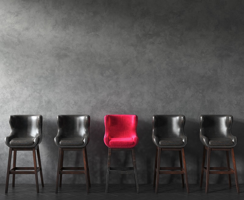 A red chair among darker chairs.