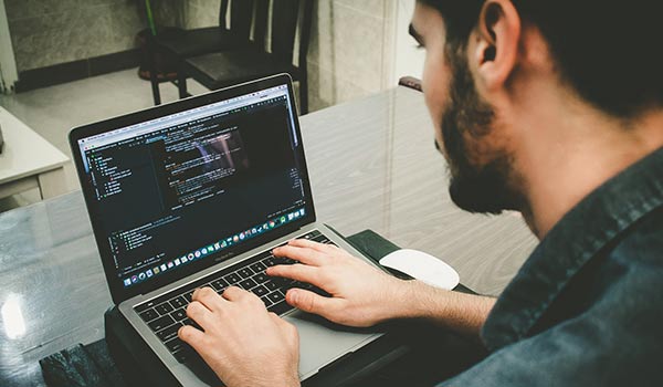 A man using a laptop to write code.