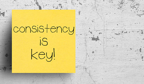 A sticky note that reads 'consistency is key'.