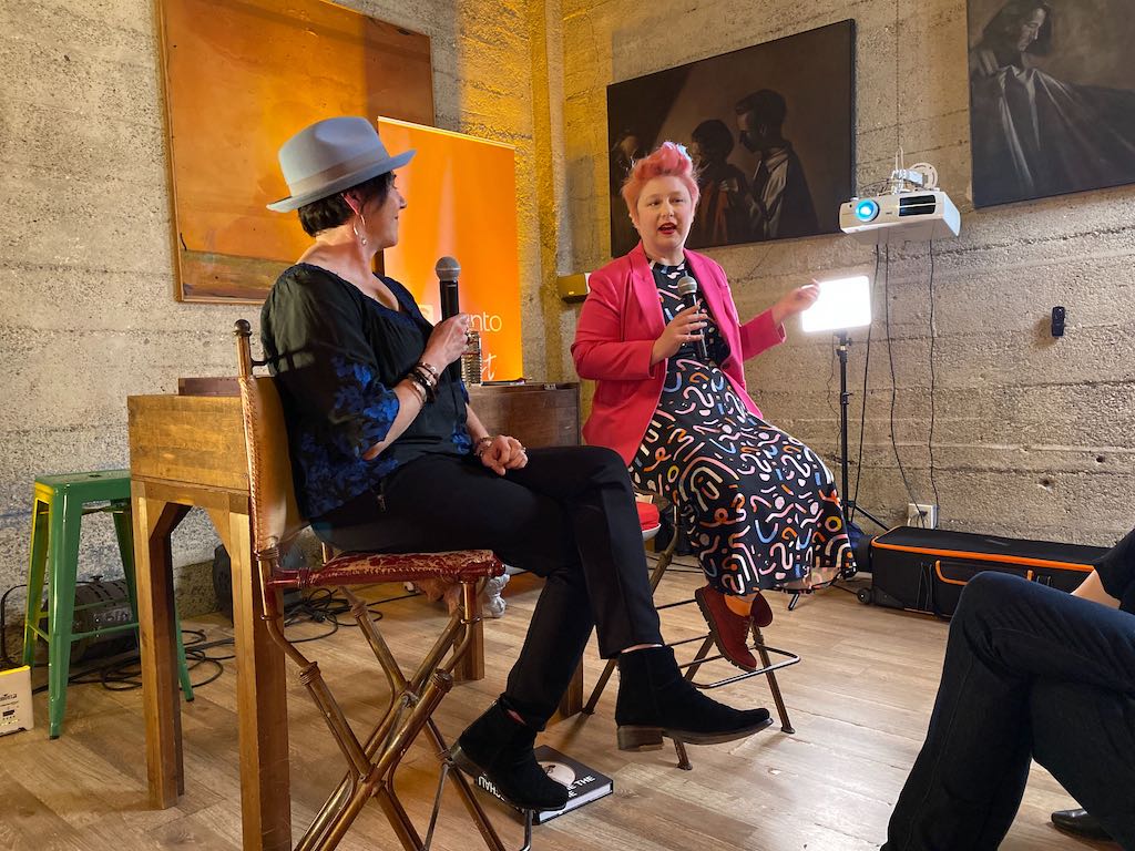 Two women sitting on a stage.