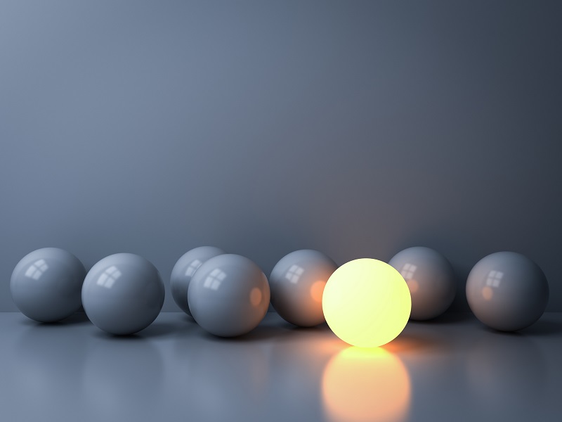 A lighted ball next to grey ones.