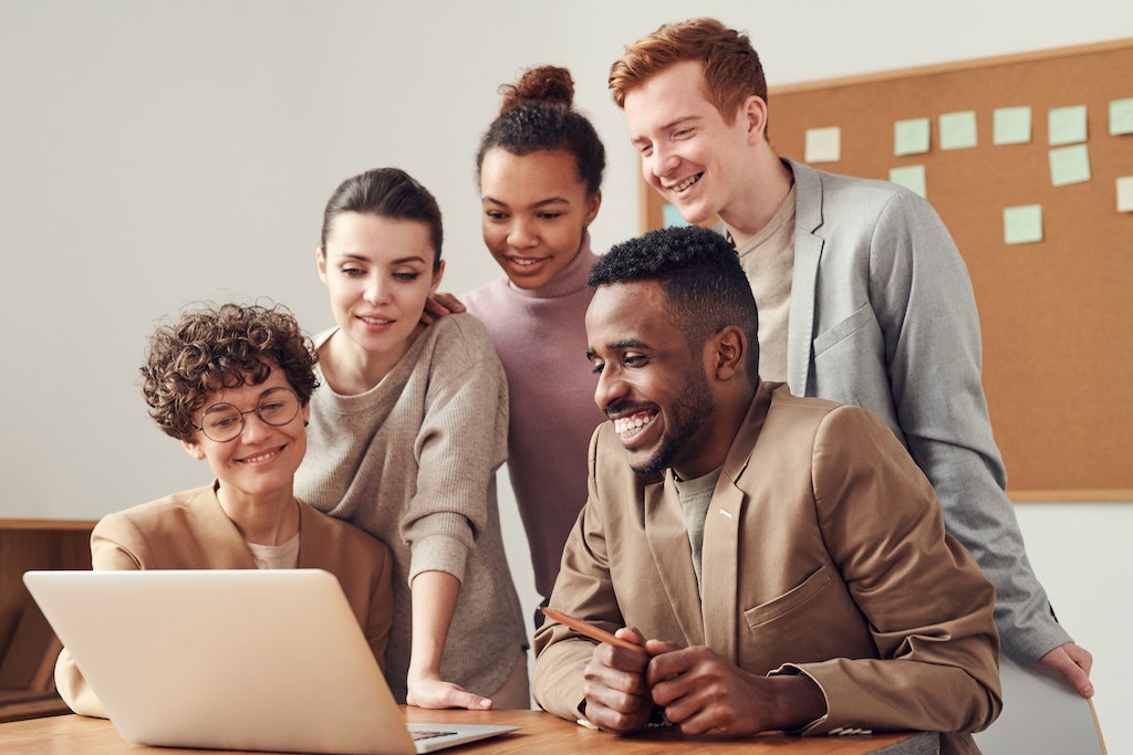 A group of excited people in front of a laptop.