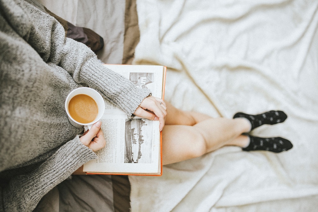 A person drinking coffee and reading a book.