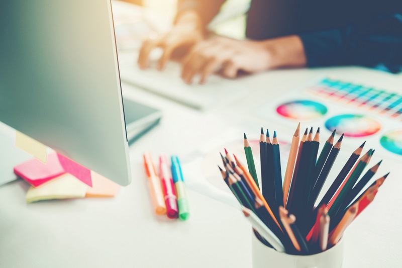 A person using a laptop next to a colorful design.