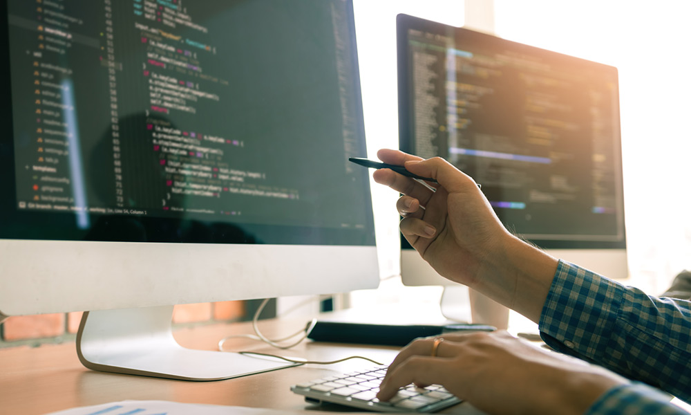 A person holding a pen to a monitor.