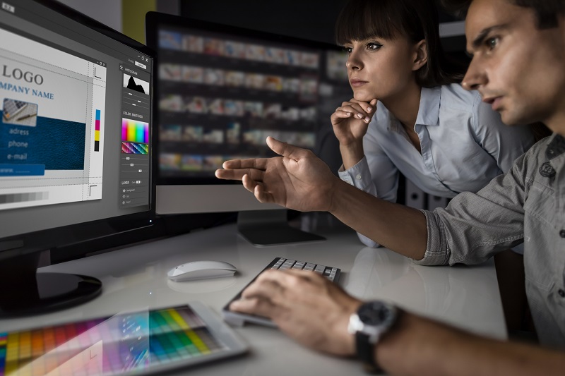 A man and woman look at a design template on a computer.