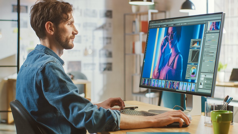 A graphic designer works on a computer on a desk.