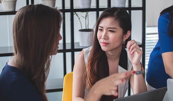 Two young women talking at work.