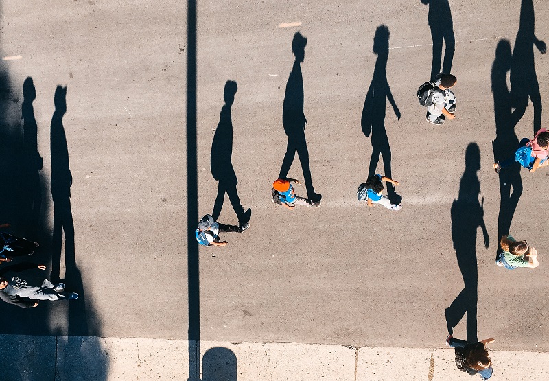 Kids walking down the street with large shadows showing.