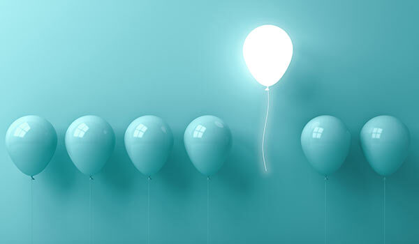 Balloons with one lit up like a lightbulb.