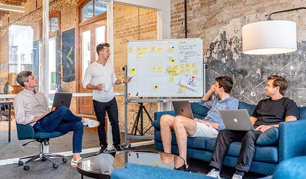 Four men in a trendy startup office discussing brand identity.