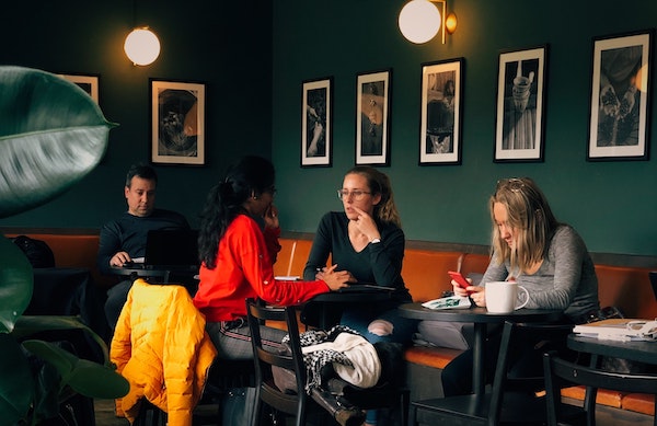 Customers sitting in a modern cafe with black-and-white photographs on the wall behind them.