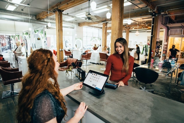 Woman ringing up a customer in a trendy, industrial business space.