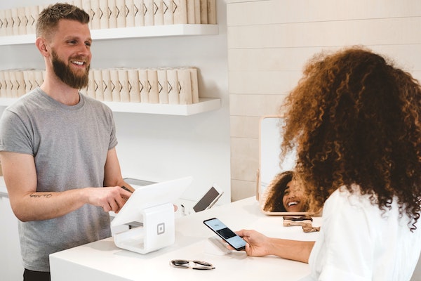 Owner collecting a customer's email address for local email marketing in a trendy small store.